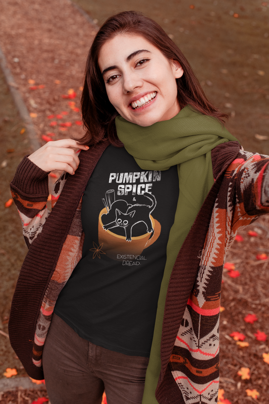 Person wearing a black t-shirt with 'Pumpkin Spice' design outdoors with fallen leaves on the ground.